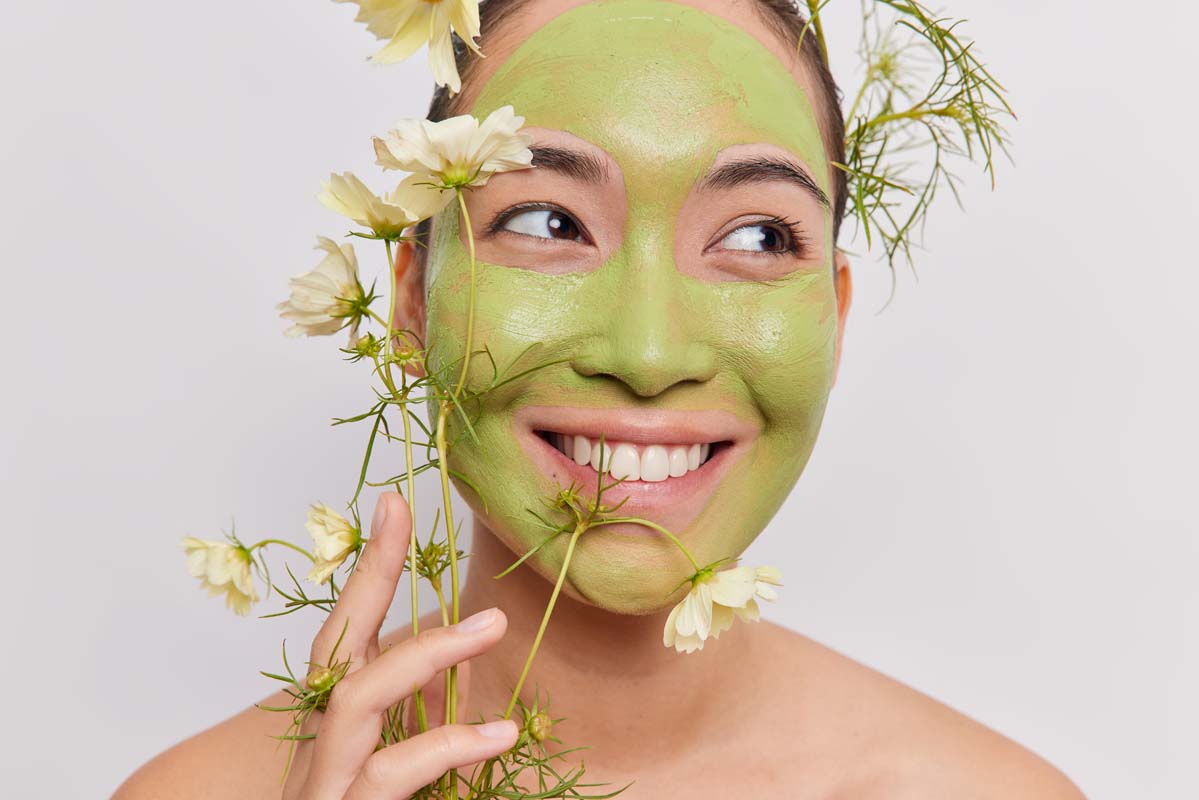 headshot of pleased asian woman applies herbal nat